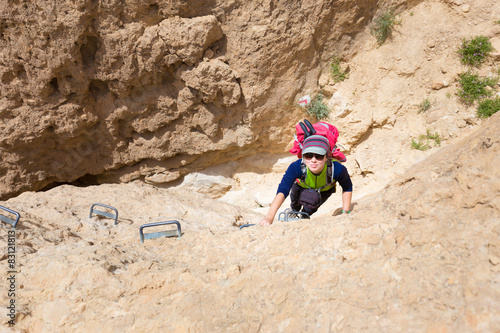 Young woman climbing desert canyon cliff.