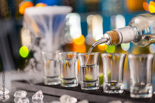 Barman pouring hard spirit into glasses
