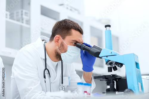young scientist looking to microscope in lab