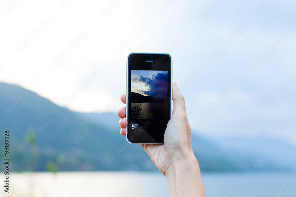 Hand taking photo of the lake landscape by smartphone