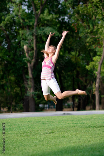 Happy Young Woman Jumping over grass