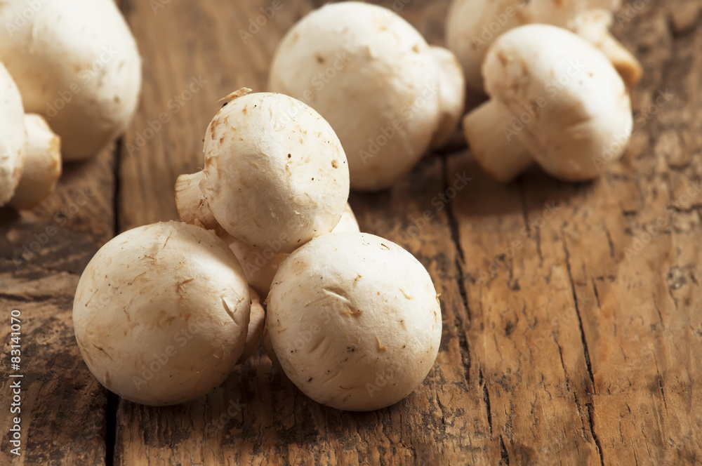 White mushrooms in a bowl on wooden table, selective focus White mushrooms in a bowl on wooden table, selective focus