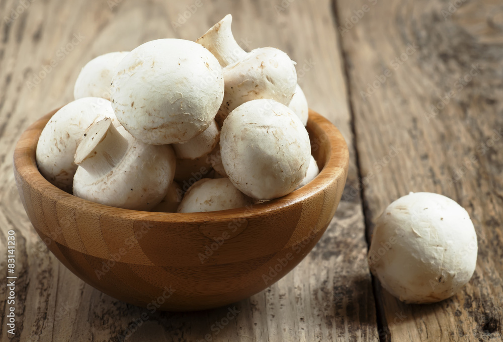 White mushrooms in a bowl on wooden table, selective focus White mushrooms in a bowl on wooden table, selective focus