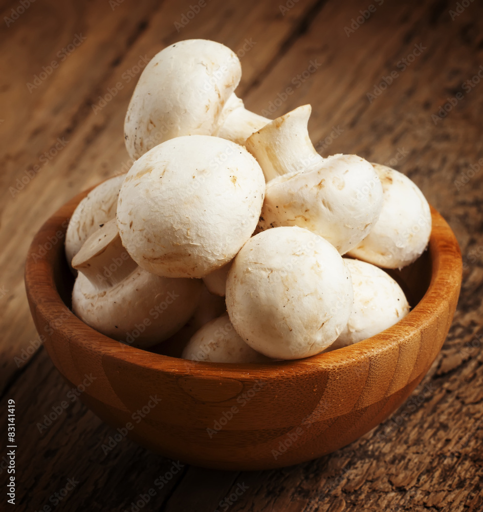 White mushrooms in a bowl on wooden table, selective focus White mushrooms in a bowl on wooden table, selective focus