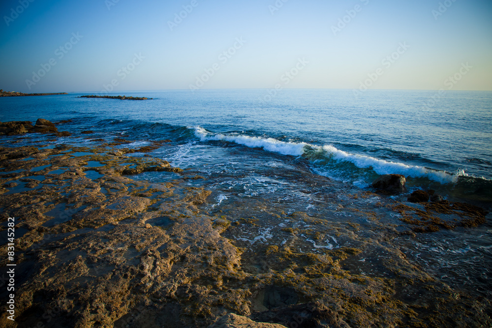 Sea waves with foam on the stony shore. Toned