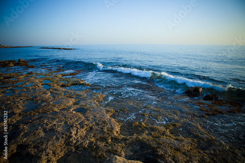 Sea waves with foam on the stony shore. Toned