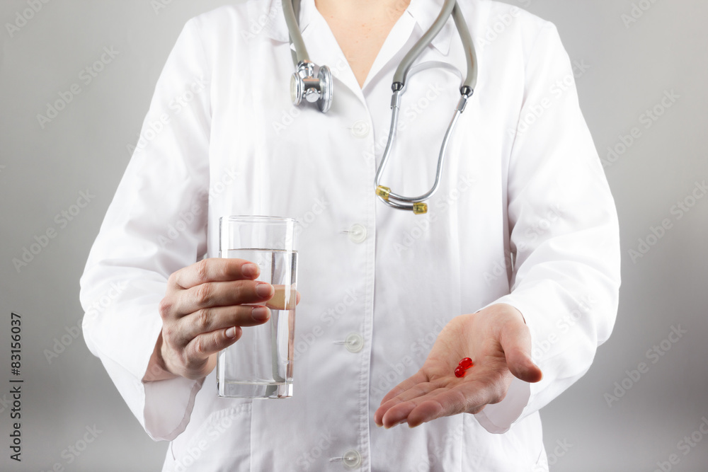 Female doctor's hand holding glass of water, giving pills. Close Female doctor's hand holding glass of water, giving pills. Close