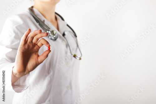 Female doctor's hand giving pills. Close up shot on grey blurred