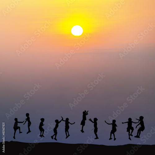 Silhouette of happy childrens jumping at sunset time