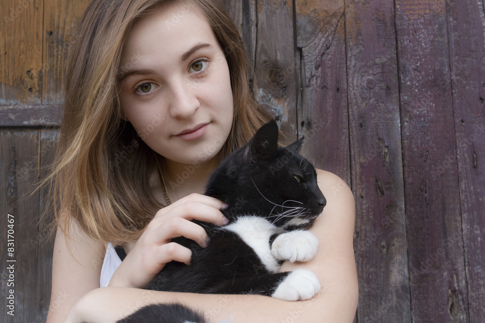 Black and white cat in hands of teenager girl