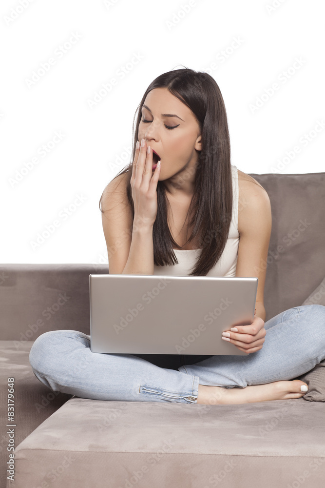 tired and sleepy young woman working on a laptop at home tired and sleepy young woman working on a laptop at home