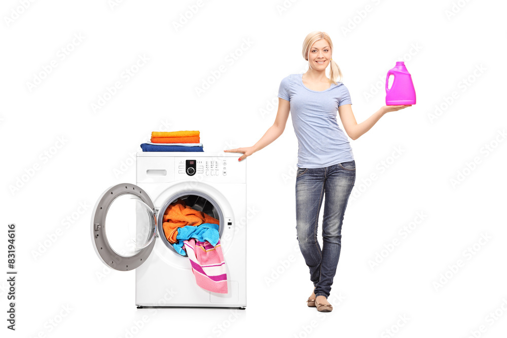 Woman holding detergent next to a washing machine Woman holding detergent next to a washing machine
