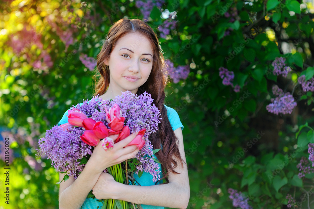 Fototapeta premium Beautiful woman holding a bouquet of tulips and lilacs