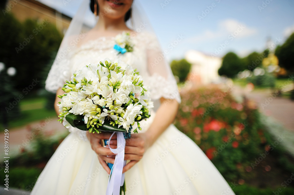 Brunette bride with bouquet near the flowers