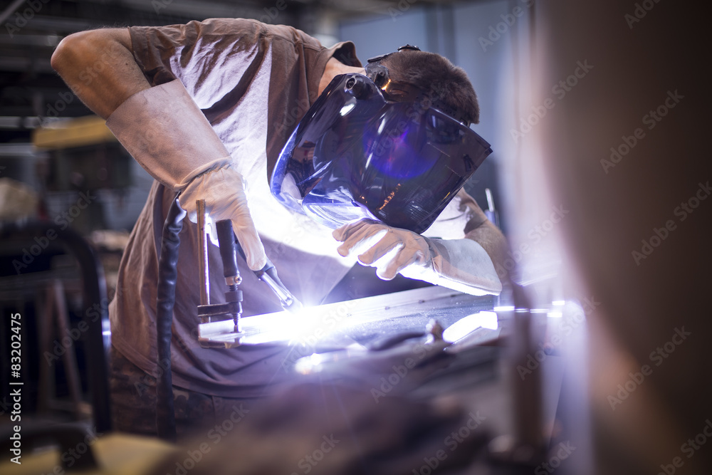 Employee welding stainless steel using welder machine - obrazy, fototapety, plakaty 