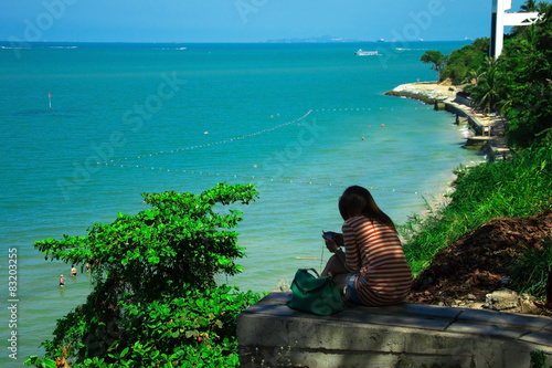 девушка в полосатой кофте сидит на фоне лазурного моря