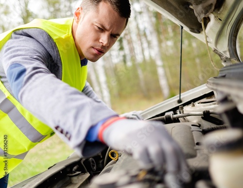 Fotografi Man fixing broken car on a roadside