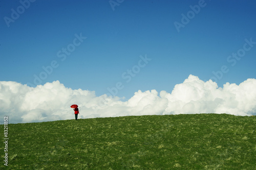 woman standing on top of a hill with a red umbrella