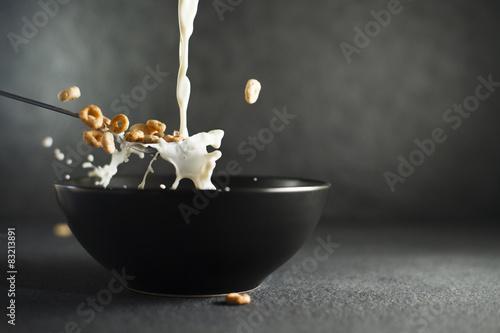 Foto Milk and cereal splashing out of spoon over bowl