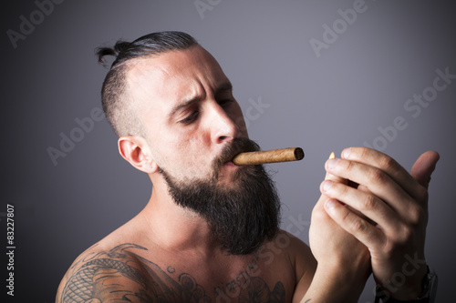 Hombre con barba encendiéndose un cigarro puro