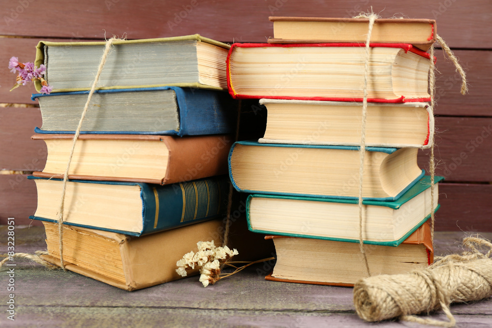 Fototapeta premium Stacks of books with dry flowers and twine on wooden background