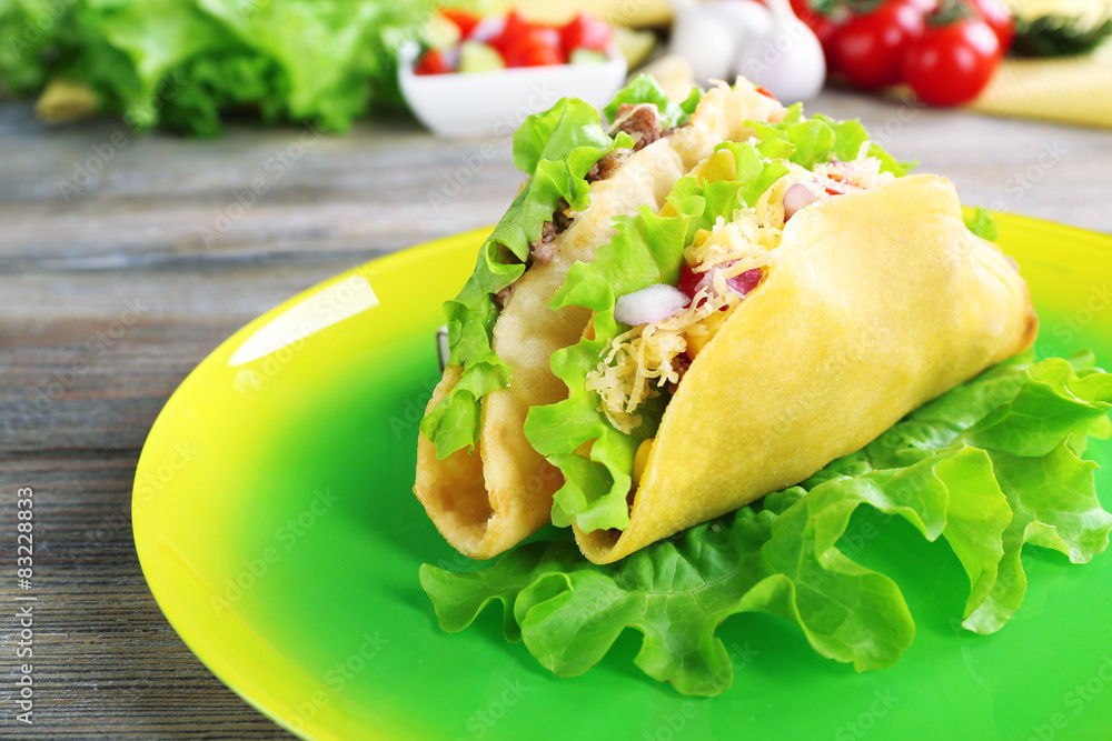 Tasty taco on plate with vegetables on table close up Tasty taco on plate with vegetables on table close up