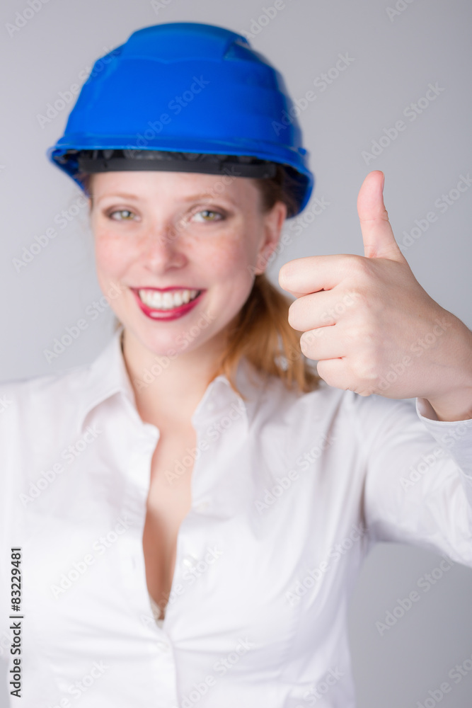 Junge Ingeneurin mit Schutzhelm und Daumen hoch Junge Ingeneurin mit Schutzhelm und Daumen hoch