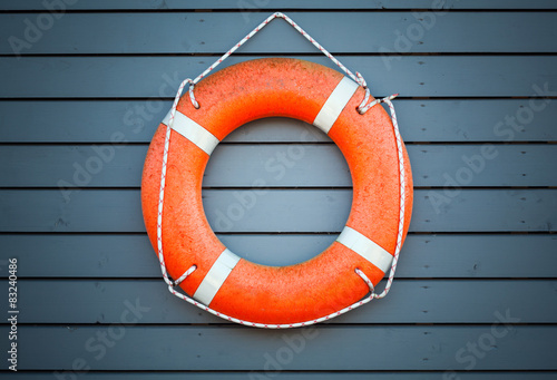 Red lifebuoy hanging on blue wooden wall photo