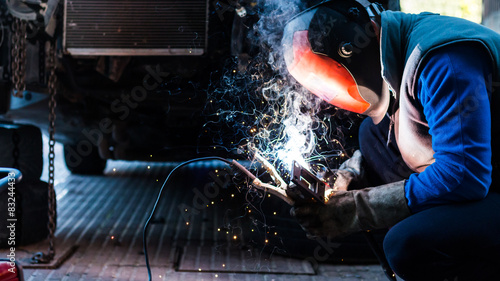 Photography skilled mechanic welding some custom parts of his car.