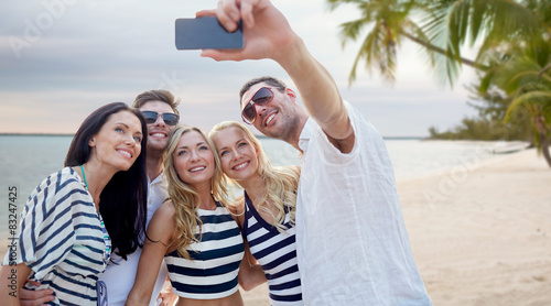 friends on beach taking selfie with smartphone