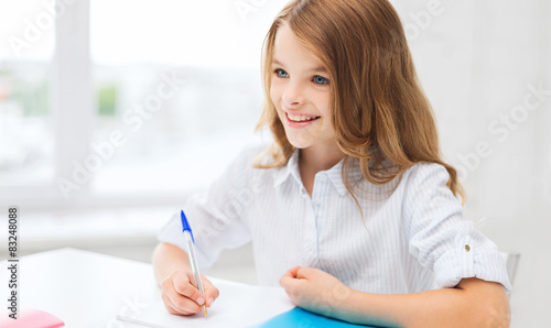 student girl writing in notebook at school