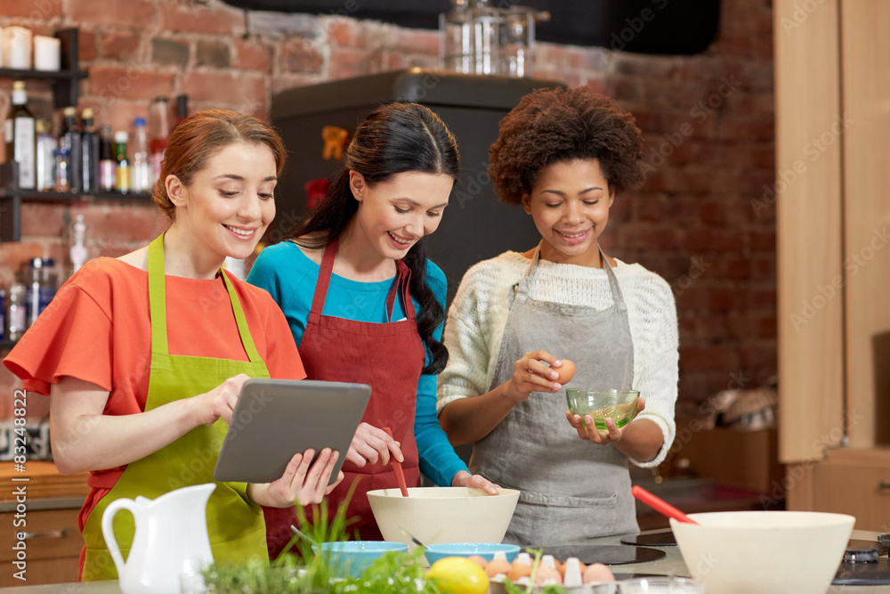 happy women with tablet pc cooking in kitchen