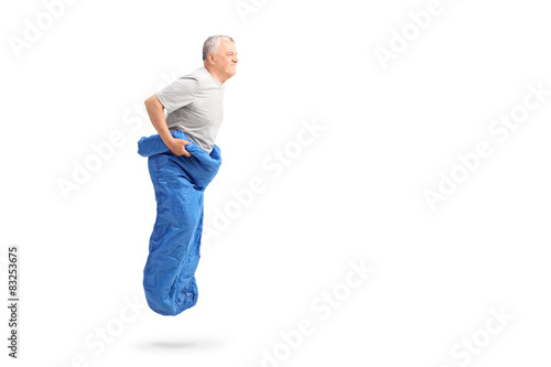 Senior man jumping in a blue sack and smiling