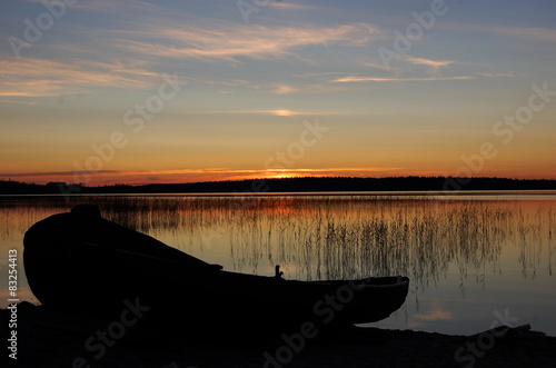 Силуэт деревянной лодки на берегу озера на закате. Карелия.