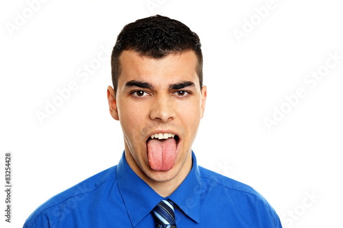 Angry young man in blue shirt sticks out his tongue on you