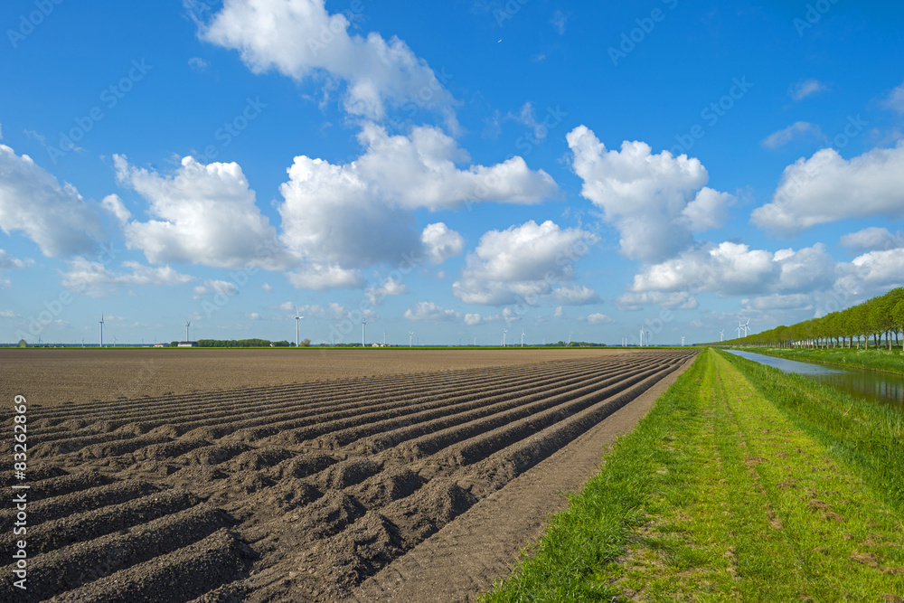 Canal along a plowed field with furrows in spring