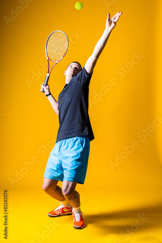 Tennis player on yellow background. Studio shot
