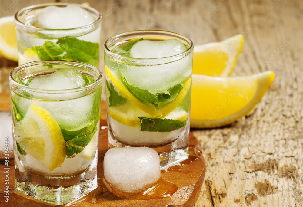 Glass of water with fresh lemon, ice and mint, selective focus Glass of water with fresh lemon, ice and mint, selective focus