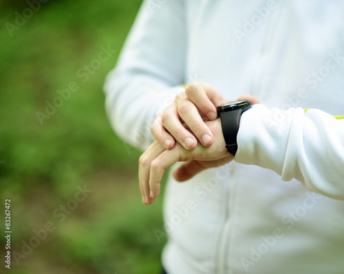 Runner on mountain trail looking at sports smart watch