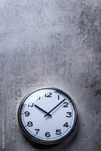 Round wall clock hanging on the grey concrete wall