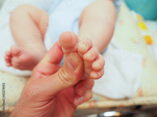 Baby receiving foot massage after diaper change with a thumb photo