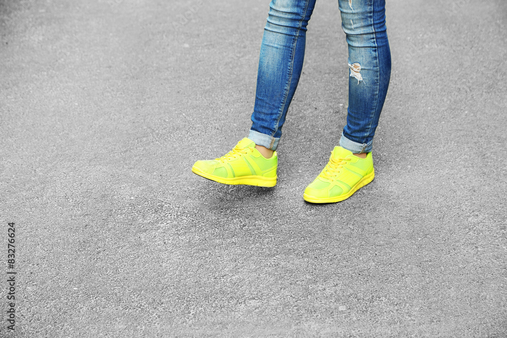 Female feet over gray asphalt background Female feet over gray asphalt background