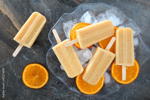 Homemade orange yogurt popsicles in an ice filled bowl photo