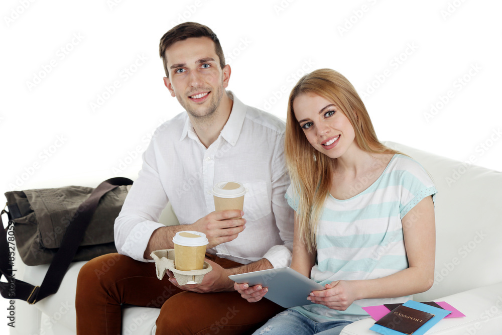 Portrait of young happy couple with baggage, sitting on sofa. isolated on white Portrait of young happy couple with baggage, sitting on sofa. isolated on white