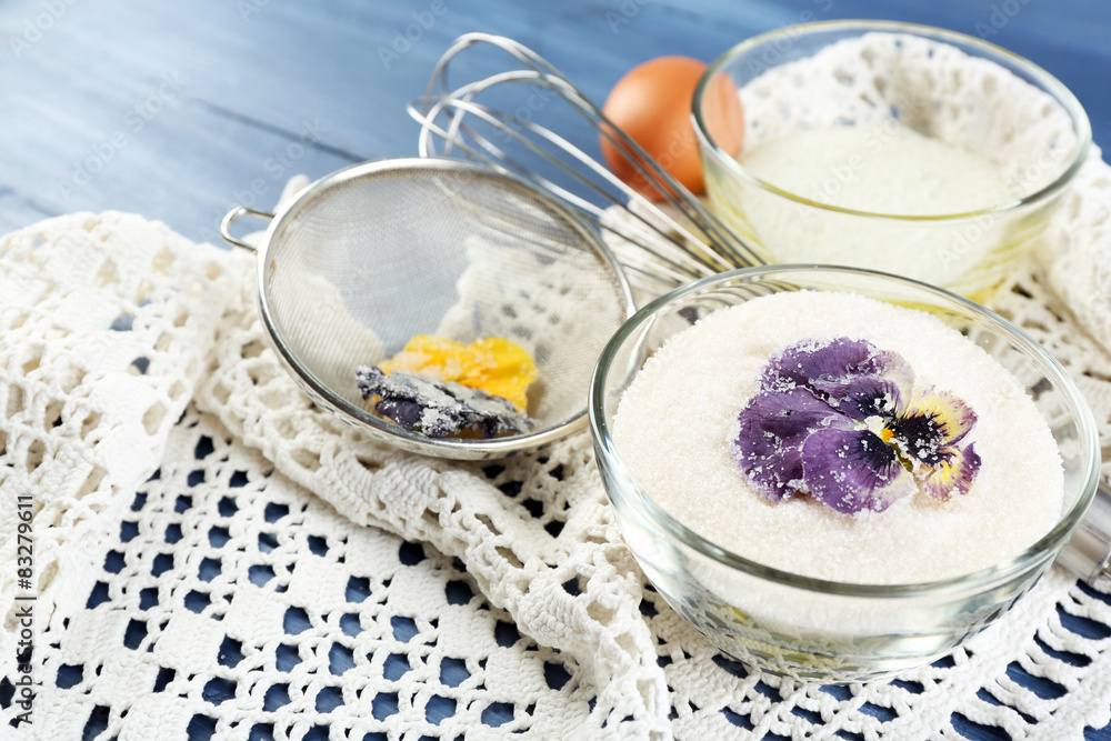 Making candied violet flowers with egg whites and sugar, on color wooden background Making candied violet flowers with egg whites and sugar, on color wooden background