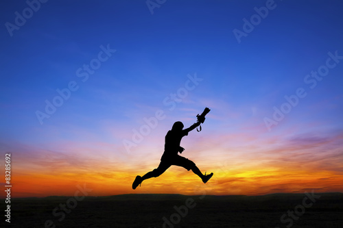 Silhouette of photographer jumping at sunset time