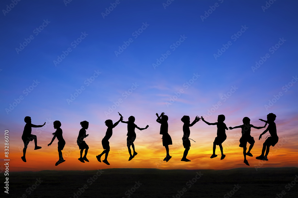 Silhouette of happy childrens jumping at sunset time