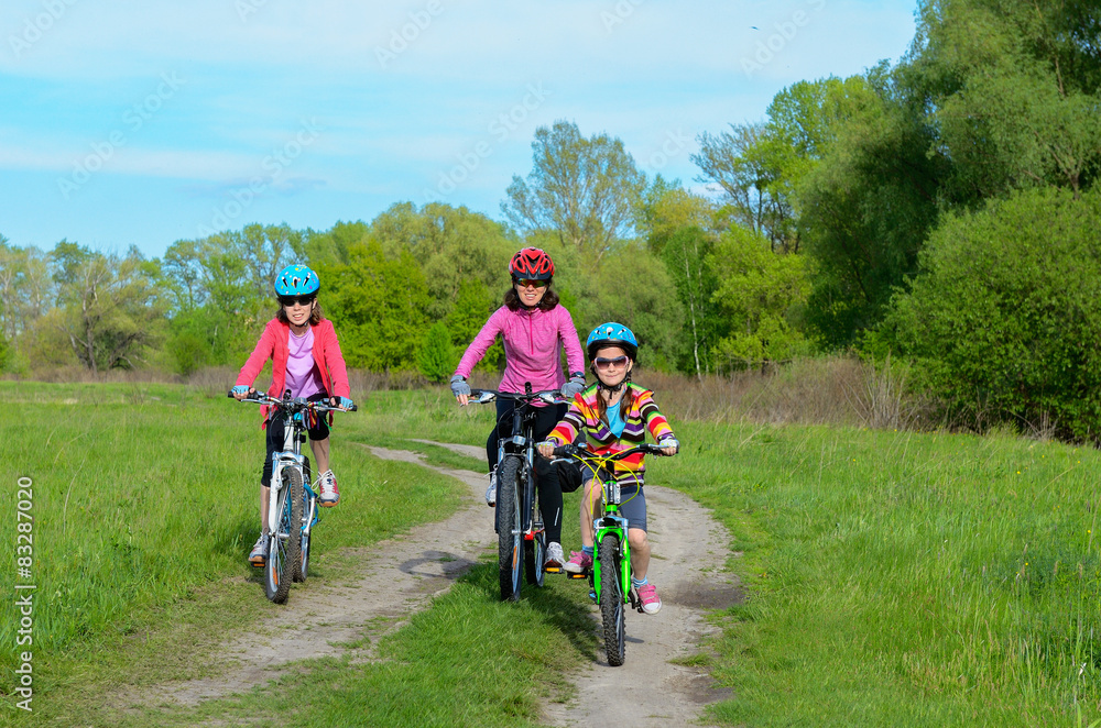 Naklejka premium Mother and kids on bikes cycling outdoors, family sport 