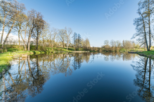 scenic reflections of trees and clouds in water © Martins Vanags
