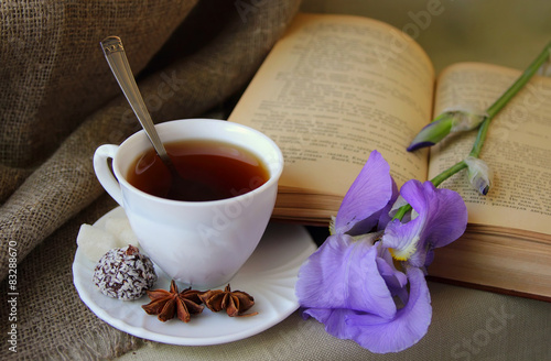 Cup of tea, open book and flower iris.